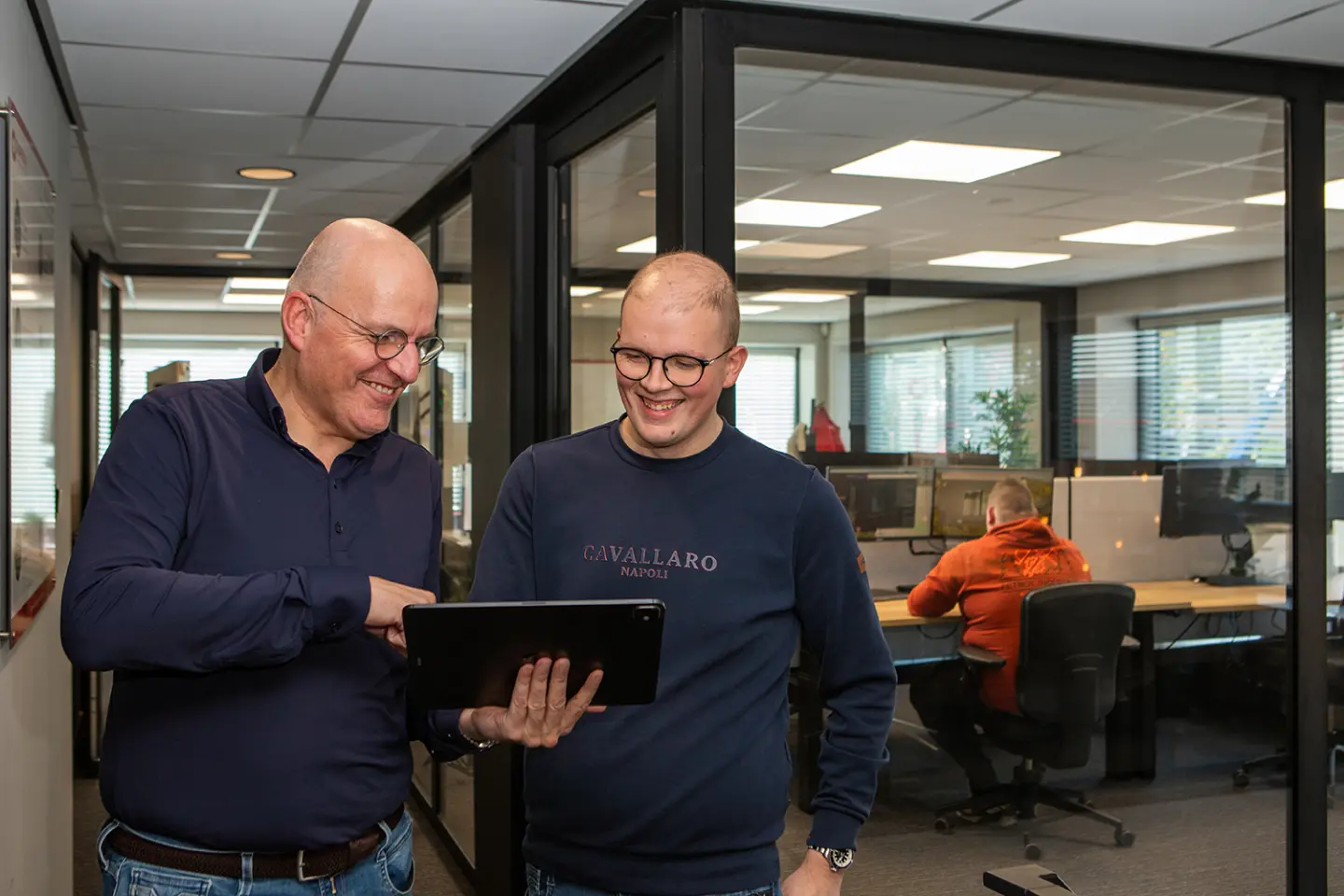 Twee collega's van Orange Bits kijken samen op een tablet in het kantoor